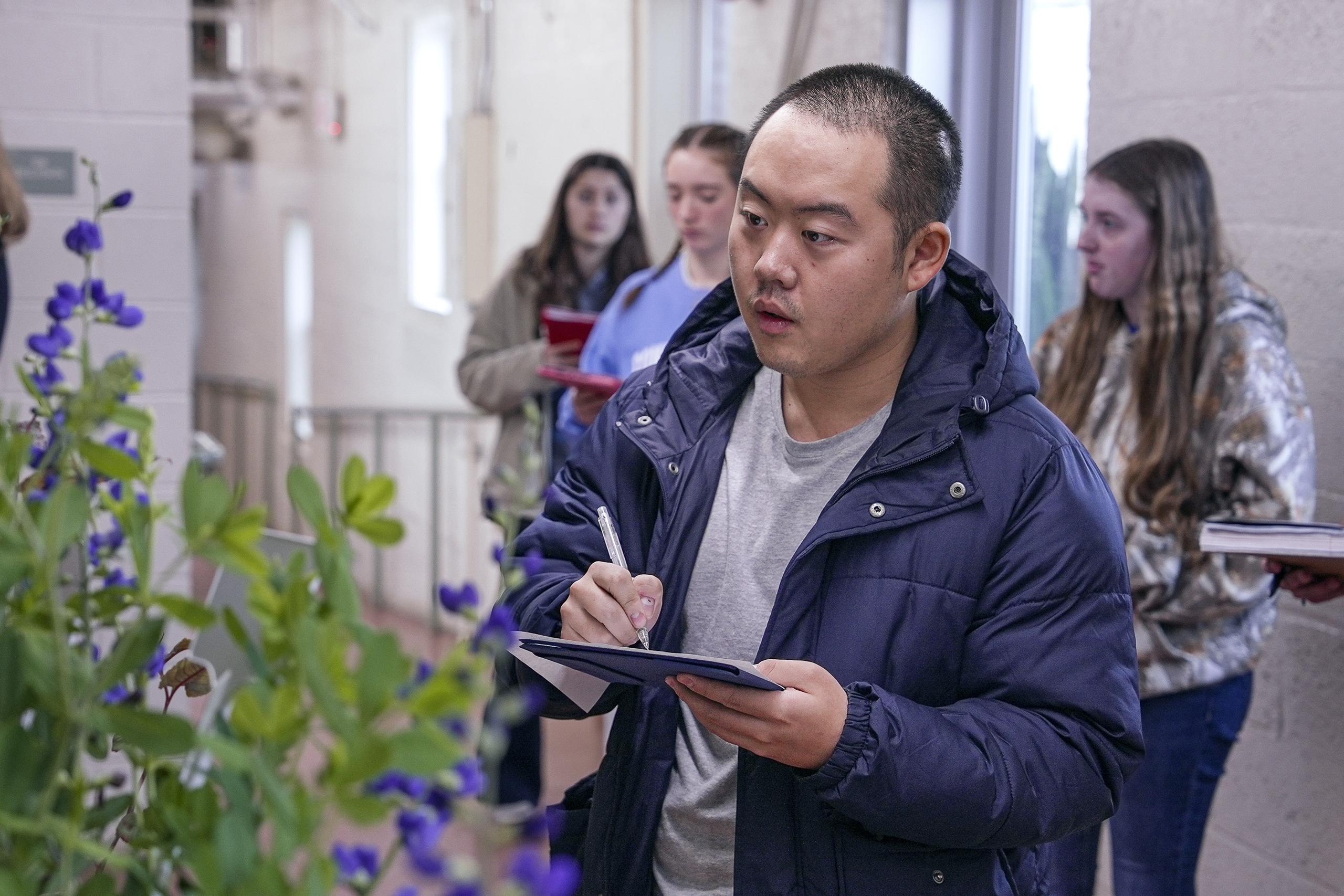 student taking notes in front of a plant