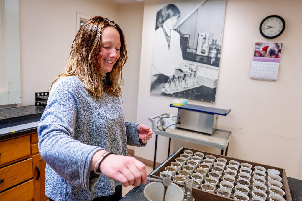 researcher loading soil samples into individual cups on a tray