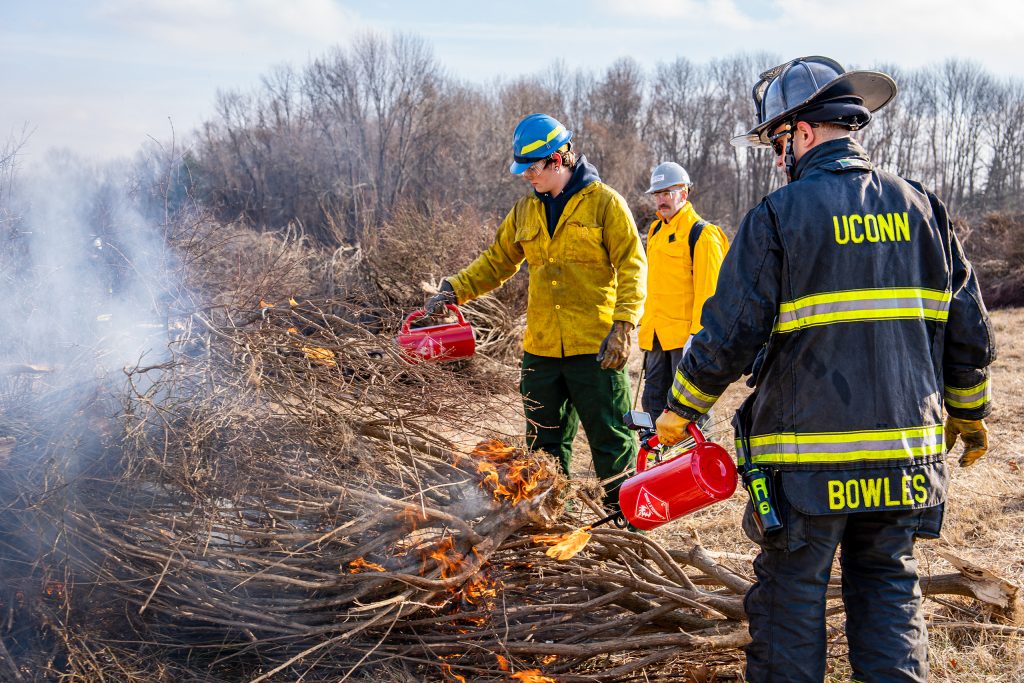 three people in protective gear, starting a prescribed fire